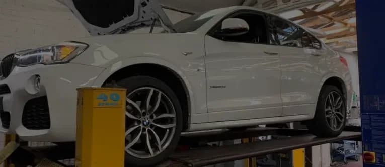 A car raised on a two-post lift in the Thatcham MOT & Service Centre workshop